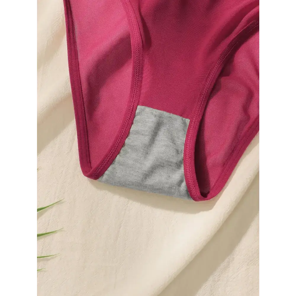 Close-up of wine red lingerie set with grey cotton gusset detail on cream fabric background