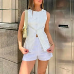 White summer office vest and shorts outfit worn by a woman with a light handbag outdoors