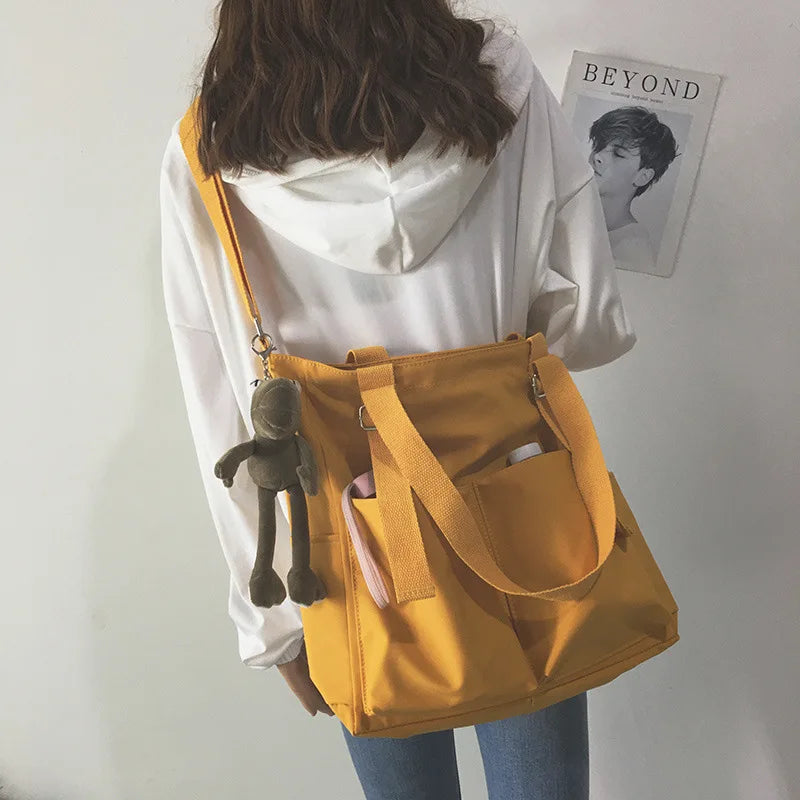 Stylish waterproof ladies handbag in yellow with exterior pockets and a cute plush keychain