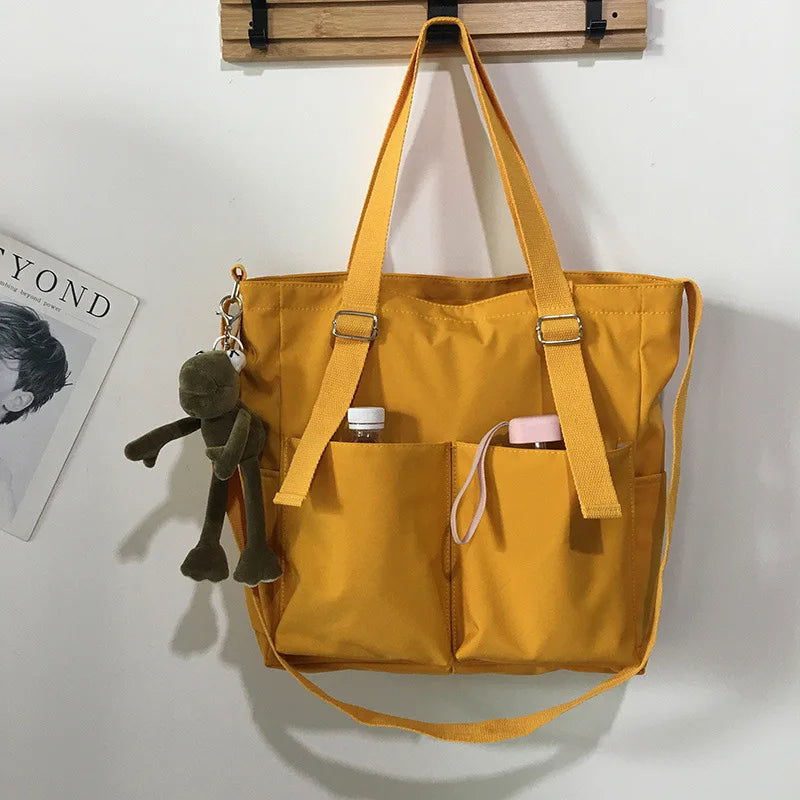 Stylish yellow waterproof ladies handbag with two side pockets and a keychain charm