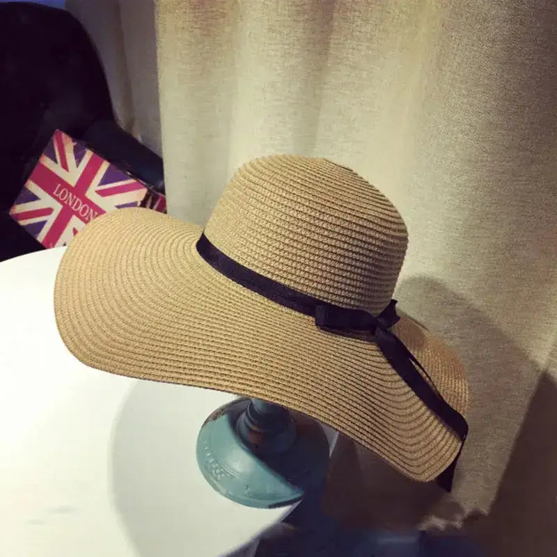 Stylish wide brim floppy hat for women in tan with a black ribbon accent