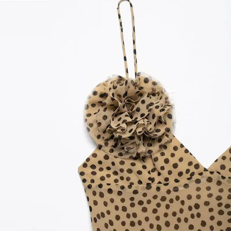 Close-up of elegant polka dot maxi dress strap with fabric rosette detail in beige and black