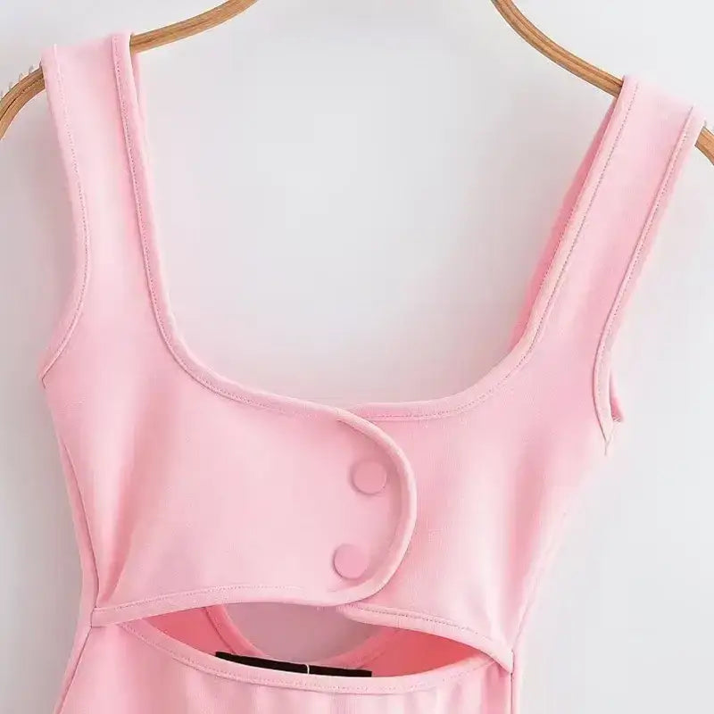 Pink mini slip dress with button detail and wide straps hanging on wooden hanger