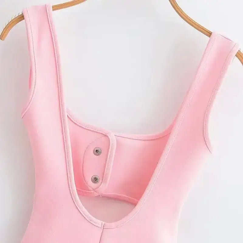 Close-up of a pink mini slip dress with wide straps hanging on a wooden hanger