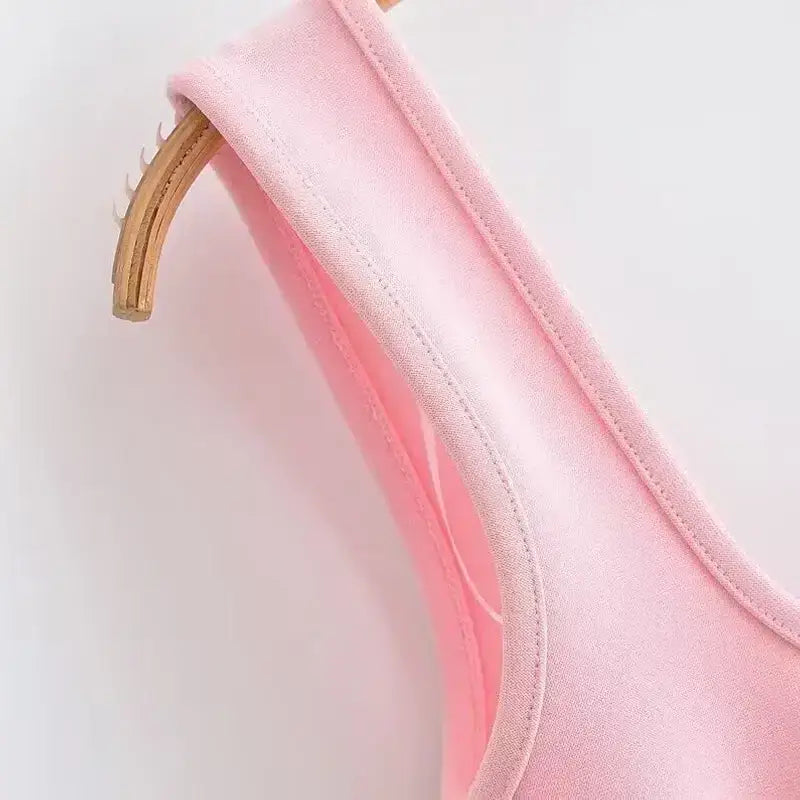 Close-up of pink mini slip dress fabric and strap on wooden hanger from The Lady's Haven Boutique