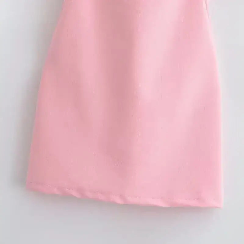 Pink fabric close-up of a mini slip dress showing smooth texture and clean hem detail