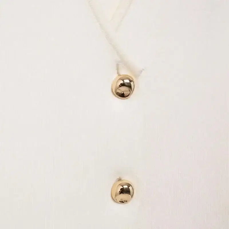 Close-up of white crop sweater vest with gold buttons from The Lady's Haven Boutique