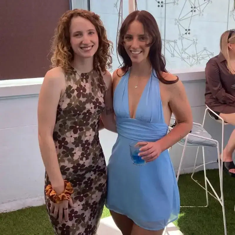 Woman wearing a blue off shoulder halter mini dress standing next to a woman in a floral dress