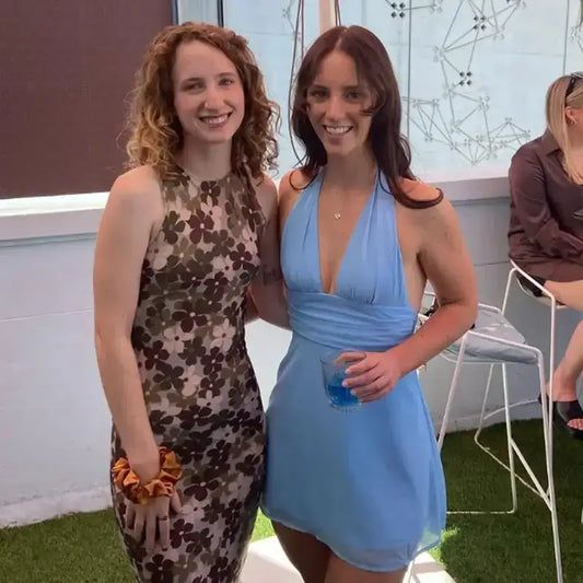 Woman wearing a blue off shoulder halter mini dress standing next to a woman in a floral dress