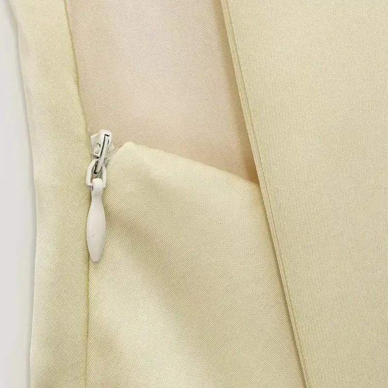 Close-up of zipper detail on beige sleeveless satin formal dress fabric for smooth closure