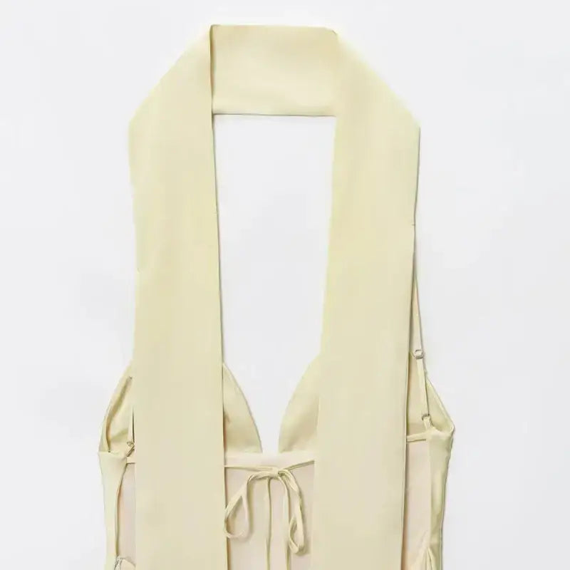 Close-up of sleeveless satin formal dress in light beige with halter neck and tie detail