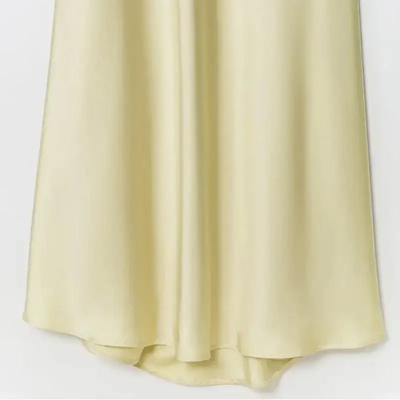 Close-up of a pale yellow sleeveless satin formal dress bottom hem showing smooth shiny fabric