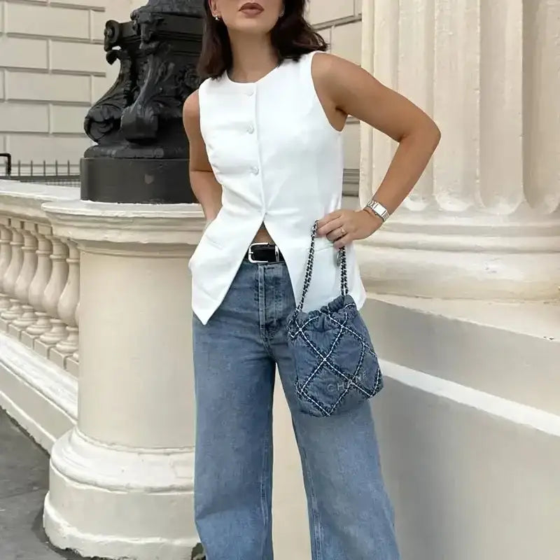 Woman wearing summer office vest and shorts outfit with white sleeveless buttoned vest and blue denim shorts