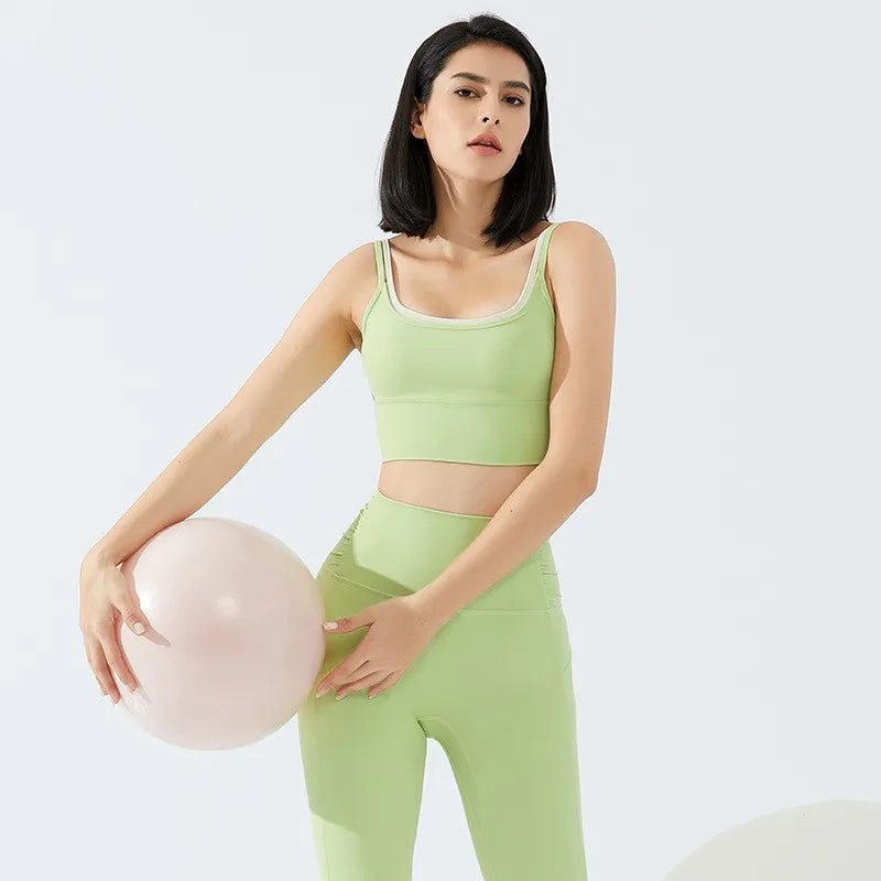 Light green yoga crop top for workout styled with matching high-waisted leggings and a fitness ball